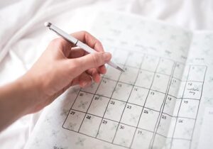 a person marking on a paper calendar that offers information to current mental health clients 