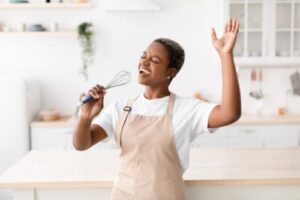 woman in kitchen sings into whisk in an eating disorder treatment program