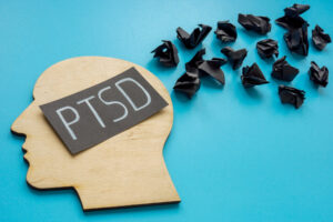 cutout of a head with PTSD written on it and thoughts flying away wondering how to calm ptsd triggers