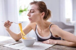 woman eating pasta and considering the most common eating disorder