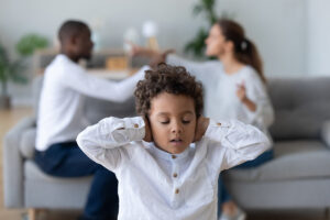 child with hands over ears considers the effects of childhood trauma