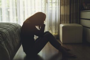 woman sitting on floor with head in hands considers the signs of untreated adhd in adults