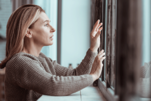 woman reaching toward window thinks about living with anxiety and managing symptoms