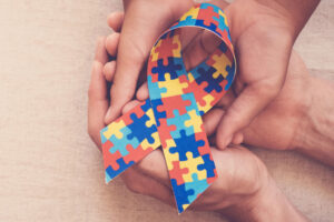 person holding a ribbon made of puzzle pieces for world autism awareness day