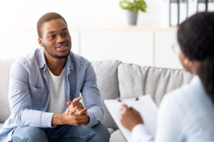 man sits on a couch listening to therapist answer his question what is psychosis