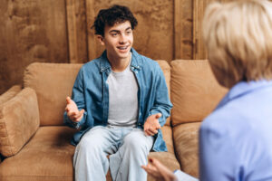 A young man speaks with a therapist. He participates in a common type of individual therapy.