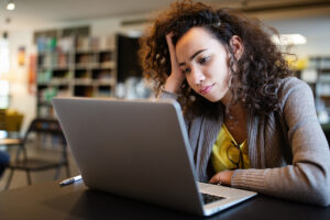woman looks at laptop and thinks about how to manage inattentive adhd