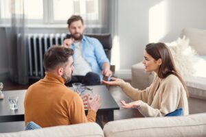 couple talking in a therapists office with animated hands and expressions