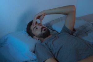 man with beard lying awake while dealing with sleep disorders