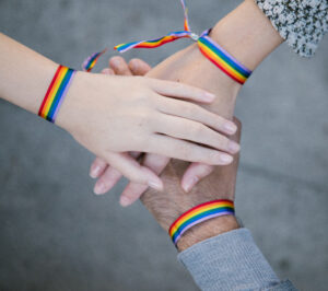 Homosexual people in rainbow bracelets stacking hands